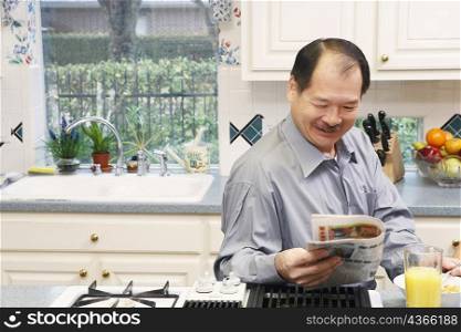 Close-up of a senior man reading a newspaper in the kitchen