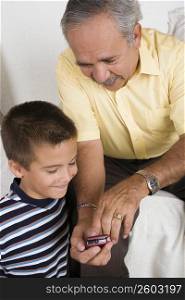 Close-up of a senior man showing a mobile phone to his grandson