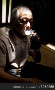 Close-up of a senior man smoking a cigar, Jinkeng Terraced Field, Guangxi Province, China