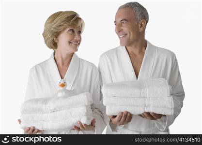 Close-up of a senior man with a mature woman standing together and holding folded towels