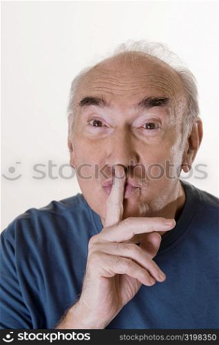 Close-up of a senior man with his finger on his lips