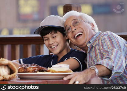 Close-up of a senior man with his grandson sitting in a restaurant and smiling