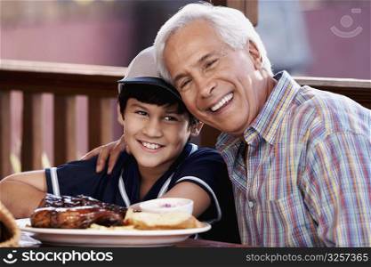 Close-up of a senior man with his grandson sitting in a restaurant and smiling