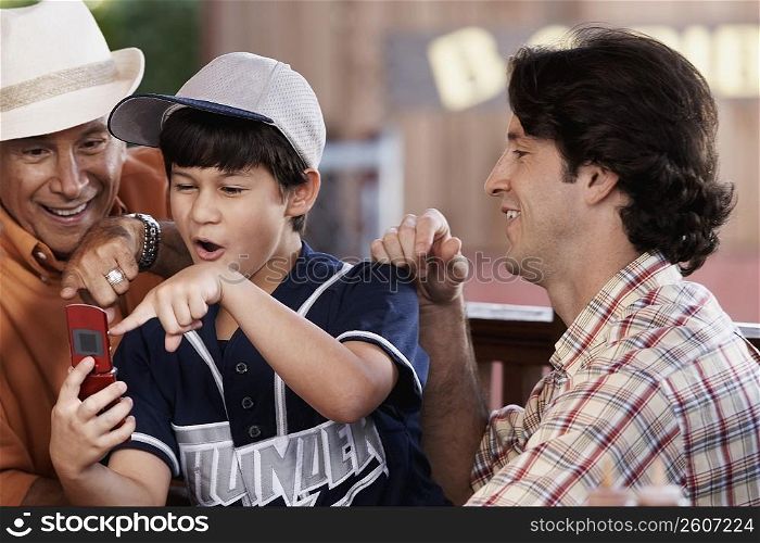 Close-up of a senior man with his son and grandson looking at a mobile phone