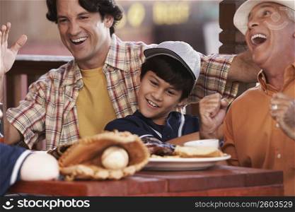 Close-up of a senior man with his son and grandson sitting in a restaurant and laughing