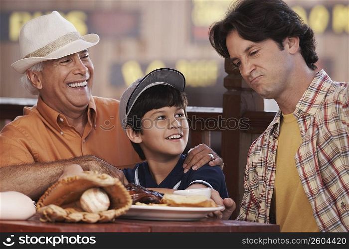 Close-up of a senior man with his son and grandson sitting in a restaurant and smiling