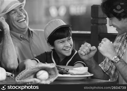 Close-up of a senior man with his son and grandson sitting in a restaurant and smiling