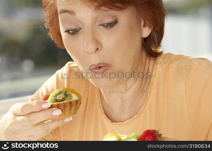 Close-up of a senior woman eating a fruit tart