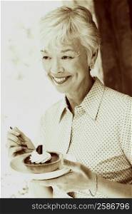 Close-up of a senior woman eating a tart with a fork
