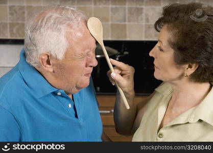 Close-up of a senior woman hitting a senior man with a ladle