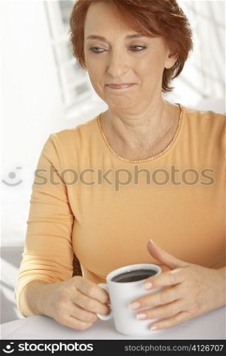 Close-up of a senior woman holding a cup of black coffee