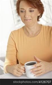 Close-up of a senior woman holding a cup of black coffee