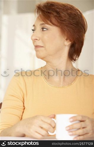 Close-up of a senior woman holding a cup of coffee looking sideways