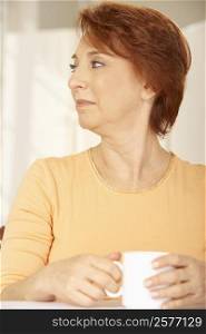 Close-up of a senior woman holding a cup of coffee looking sideways