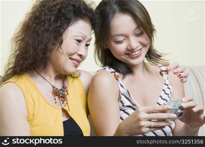 Close-up of a senior woman sitting with her granddaughter and looking photographs in a digital camera
