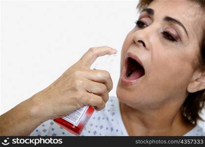 Close-up of a senior woman spraying mouthwash into her mouth