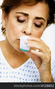 Close-up of a senior woman taking medicine from a measuring cup