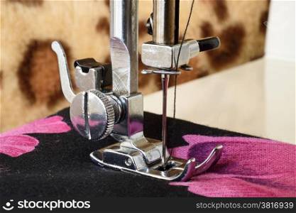Close up of a sewing machine with the needle sewing a colorful fabric