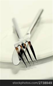 Close up of a silver knife and fork on a white background with copyspace