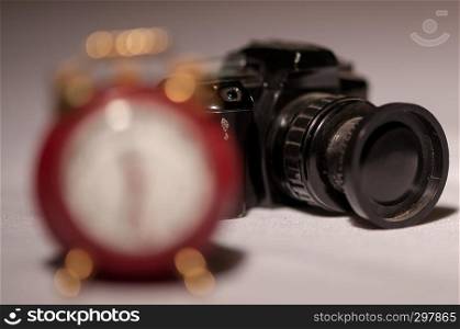 Close-up of a small camera in the background and a clock in the foreground