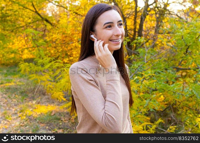 Close up of a smiling pretty young girl with wireless earphones outside