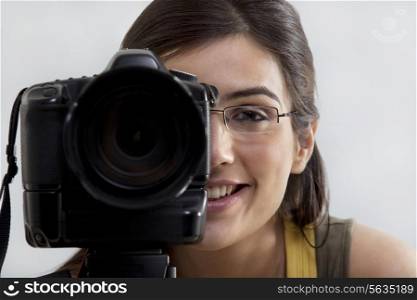Close-up of a smiling young woman taking a photograph