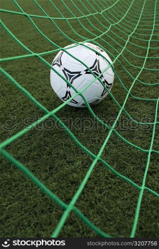 Close-up of a soccer ball in a goal post net