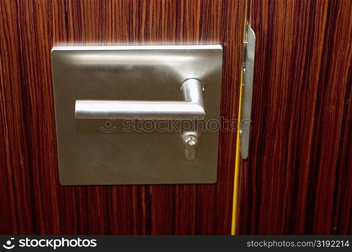 Close-up of a steel door handle on a closed wooden door