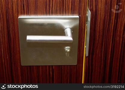 Close-up of a steel door handle on a closed wooden door