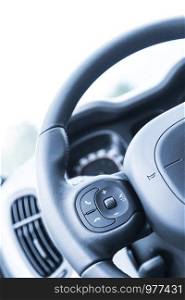 Close up of a steering wheel with remote control, blurry dashboard