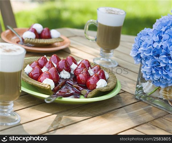 Close-up of a strawberry tart and two glasses of chocolate milkshake on a table