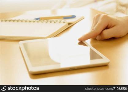 Close up of a student hand searching in a tablet on a desk at home