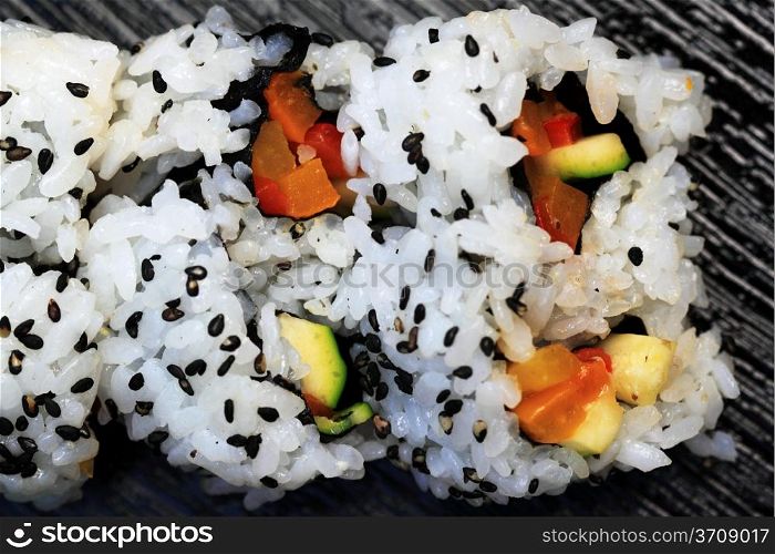 Close up of a sushi California roll on a black board.
