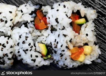 Close up of a sushi California roll on a black board.