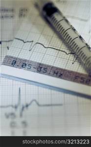 Close-up of a syringe on an ECG report