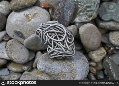 Close-up of a tangled aluminum wire on pebbles