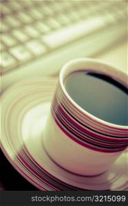 Close-up of a tea cup with a computer keyboard