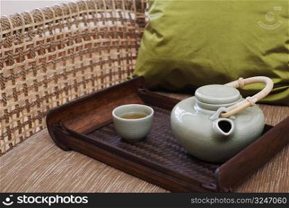 Close-up of a teapot and a tea cup with a tray in an armchair