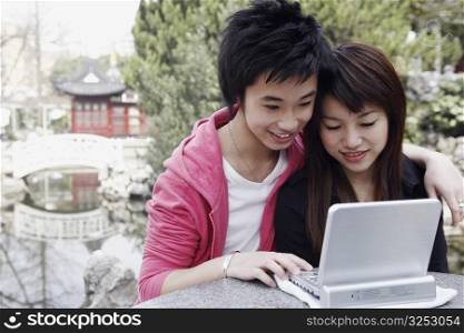 Close-up of a teenage boy and a young woman using a laptop