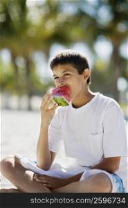 Close-up of a teenage boy eating a slice of watermelon