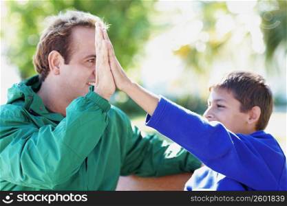Close-up of a teenage boy giving hi-five to his father