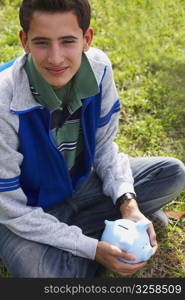 Close-up of a teenage boy holding a piggy bank
