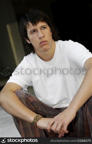 Close-up of a teenage boy sitting with his hands on his knees