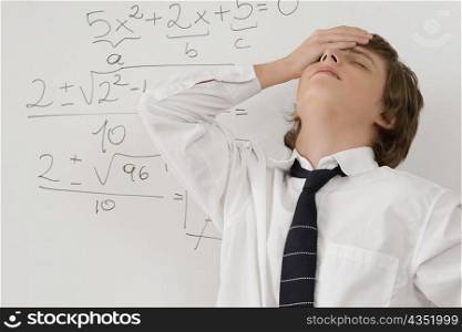 Close-up of a teenage boy standing in front of a whiteboard and looking stressed