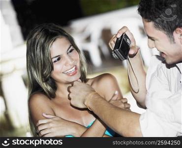 Close-up of a teenage boy taking a picture of a young woman