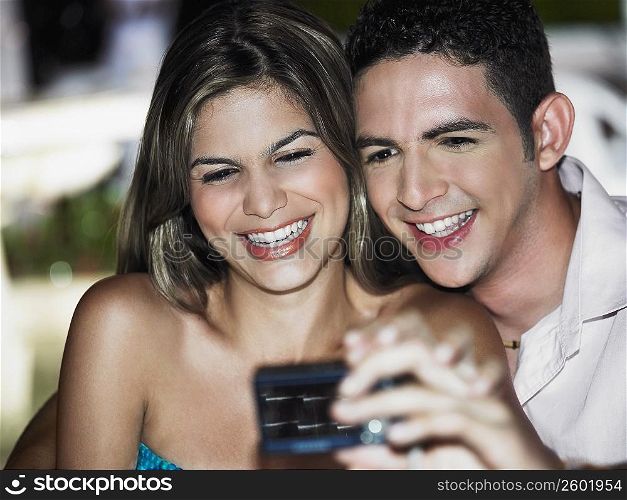 Close-up of a teenage boy taking a picture of himself with a young woman