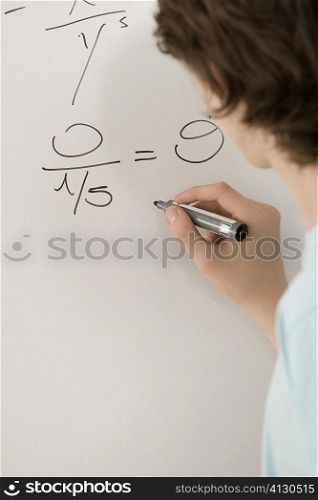 Close-up of a teenage boy writing on a whiteboard