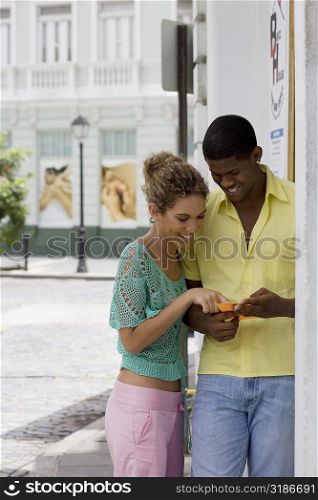 Close-up of a teenage girl and a young man looking at paper and smiling