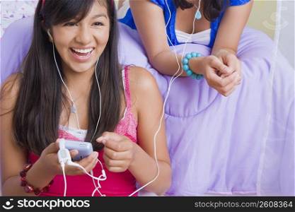 Close-up of a teenage girl and a young woman listening to music with ear buds and smiling