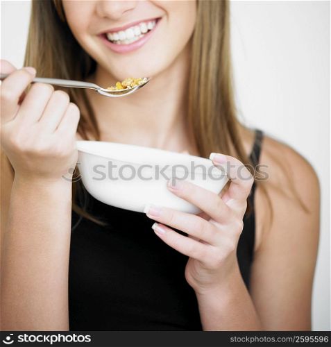 Close-up of a teenage girl holding a bowl and a spoon of corn flakes